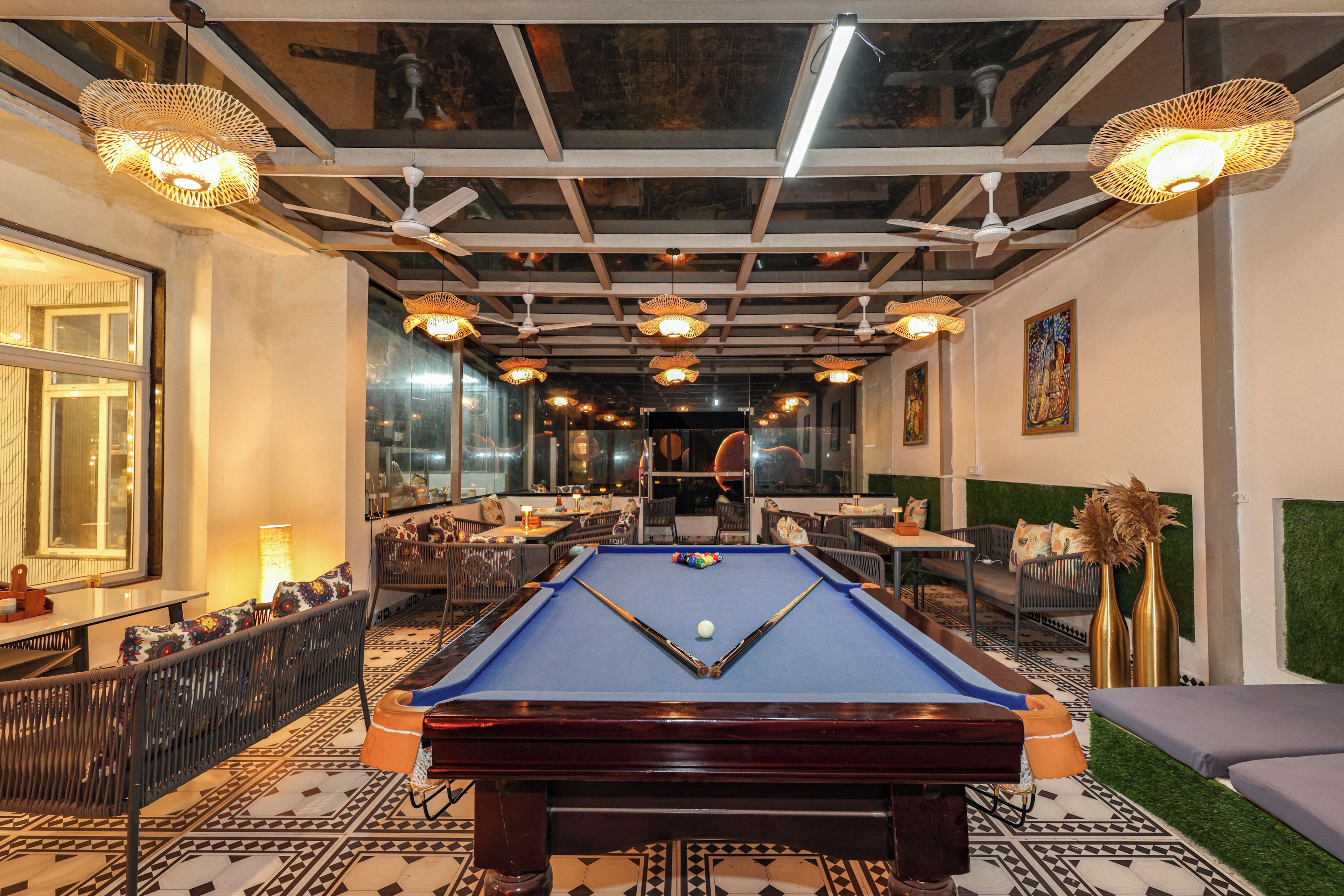 A pool table in a room with a patterned floor, ceiling fans, and hanging lights.