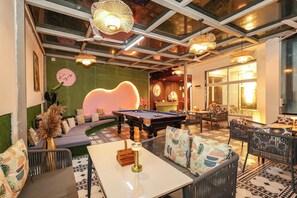 A billiards room with a pool table, seating areas, and decorative lighting. - Kyro Nest and Notch (Mussoorie)