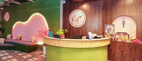 A reception desk with a green counter, a wooden wall, and a sign that reads 'Kyro'.