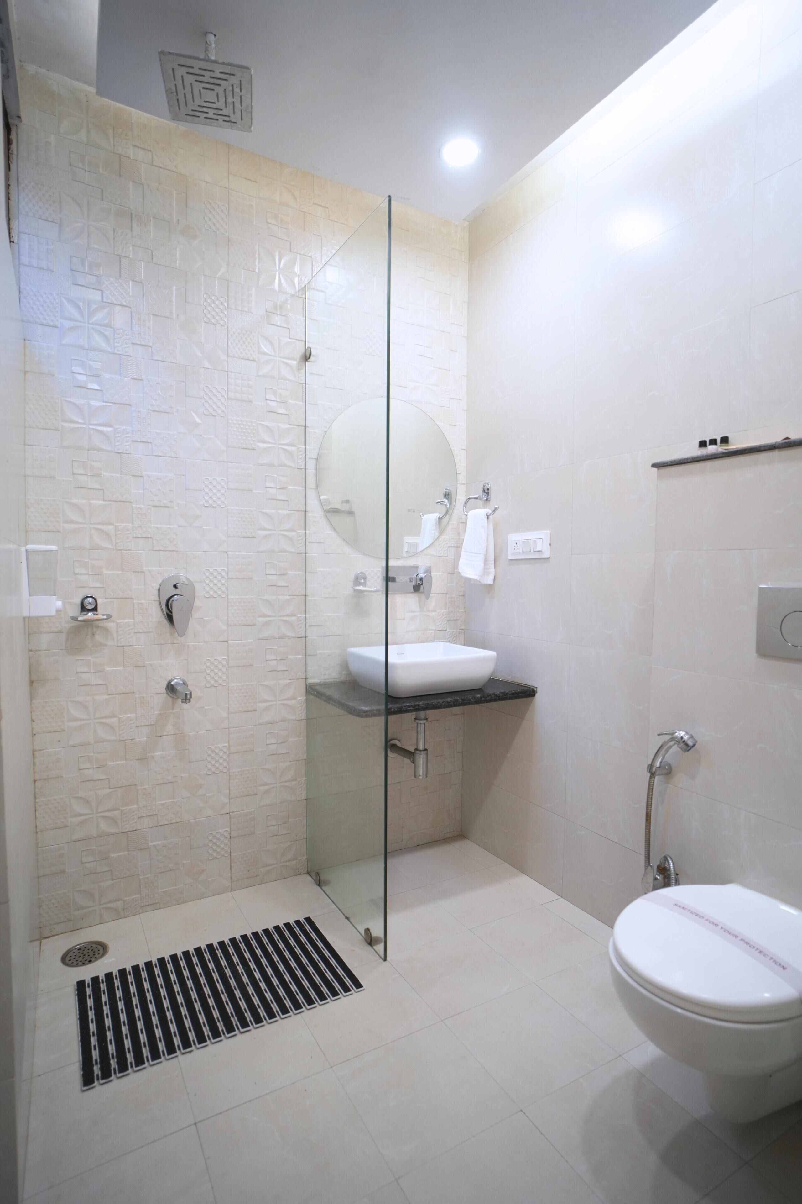 Un baño moderno con ducha envuelta en vidrio, lavamanos blanco y retrete.