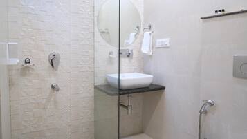 Un baño moderno con ducha envuelta en vidrio, lavamanos blanco y retrete.