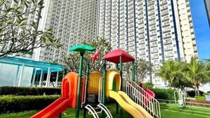 A playground with slides and climbing structures, surrounded by tall residential buildings.
