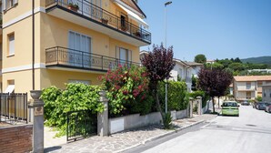A multi-story residential building with balconies, a stone-paved sidewalk, and a clear sky. - Just minutes from downtown and the beach, elegant BnB in Sirolo (Sirolo)
