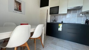Une cuisine moderne avec des meubles blancs et noirs, un four à micro-ondes encastré et un dosseret carrelé.