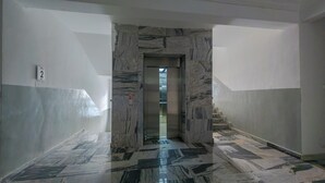 A marble-floored hallway with a door leading to an elevator. - Luxe 1BR Retreat in Ikoyi • Pool • Fast WiFi • Near Beach (Ikoyi)