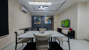 A modern meeting room with a large table, comfortable chairs, a flat-screen TV, and decorative wall art.
