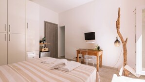 A bedroom with a bed, a desk, a TV, and a wooden tree branch decoration. - ~The Cirrus Guesthouse~ (Sirolo)