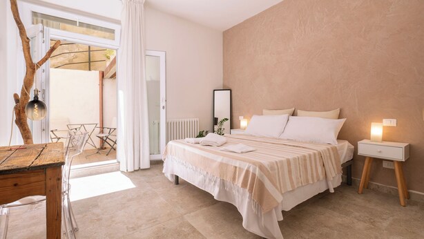 A bedroom with a bed, bedside tables, a mirror, and a view of the outside. - ~The Cirrus Guesthouse~ (Sirolo)