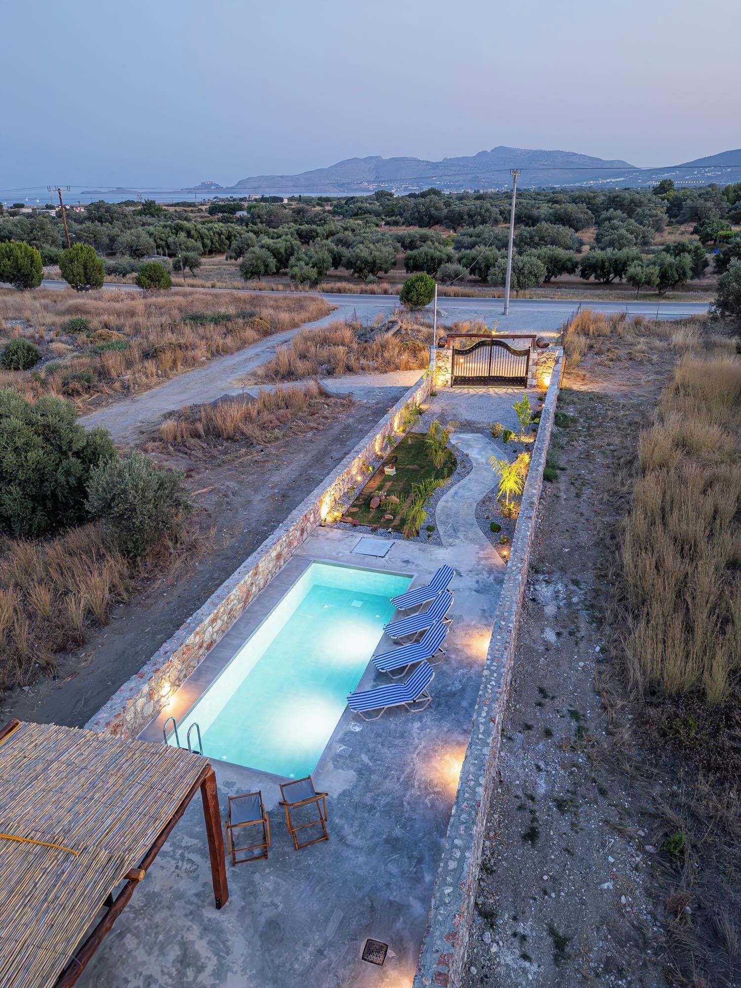 A swimming pool with lounge chairs, a wooden deck, and a view of the surrounding landscape.