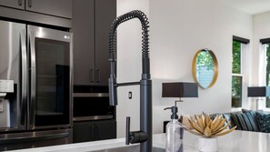 Una cucina moderna con elettrodomestici in acciaio inossidabile, un rubinetto nero e un design minimalista.