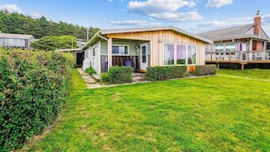 A two-story house with a front porch, a covered patio, and a well-maintained lawn. - Cape Escape - New Oceanfront Listing! (Arch Cape)