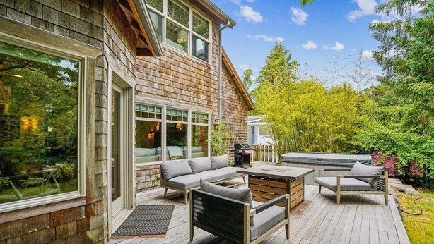 A wooden deck with outdoor furniture, including sofas and chairs, and a barbecue grill.