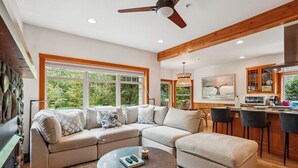 A modern living room with a sectional sofa, a round coffee table, and a dining area with bar stools.