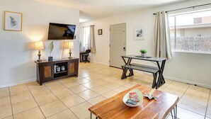 Una sala de estar con televisor, mesa de madera, banco, aparador y puerta.