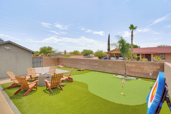 A backyard with artificial grass, a fire pit, and wooden chairs. - 6 Mi to Dtwn: Tucson Gem w/ Outdoor Oasis! (Tucson)