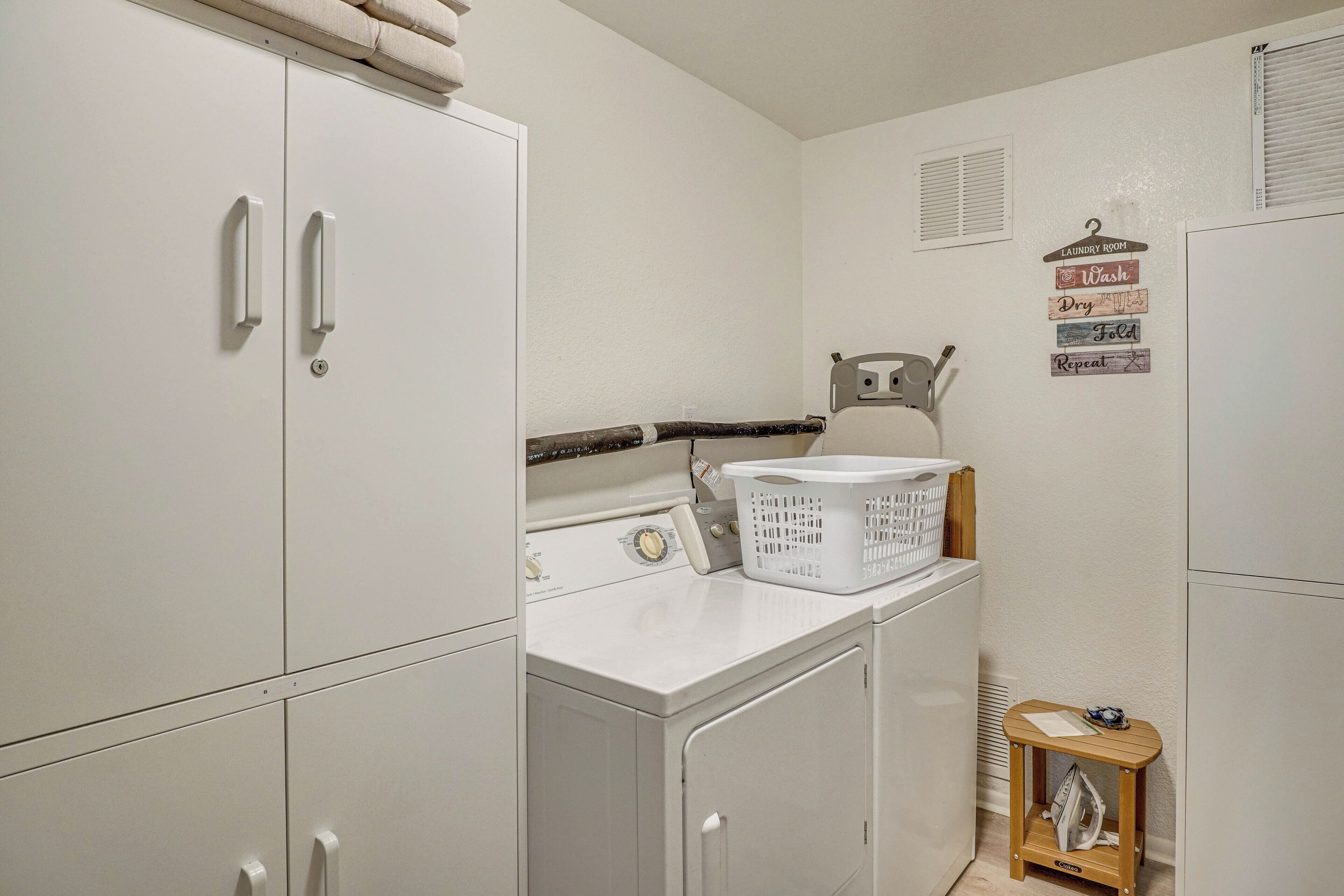 Une buanderie équipée d’un lave-linge, d’un sèche-linge et d’une petite table en bois sur laquelle se trouve un panier.