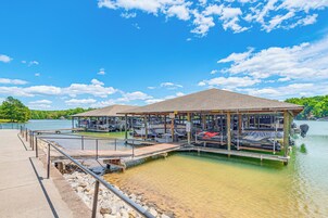 Un bote amarrado con una zona de estar cubierta, un muelle y un lago.