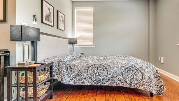 A bedroom with a bed, a bedside table with a lamp, a wall-mounted telephone, and framed pictures. - Steps to Smith Mountain Lake: Unit w/ Pool Access! (Huddleston)