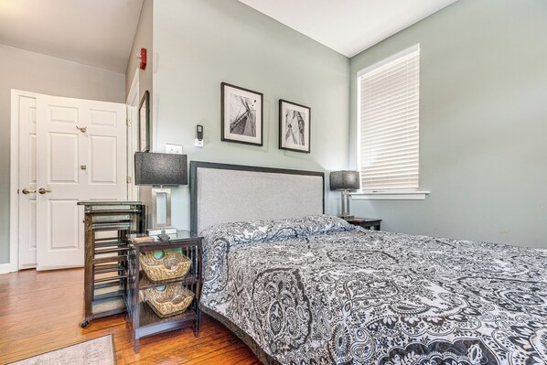 A bedroom with a bed, a nightstand, a lamp, a chair, and a door.