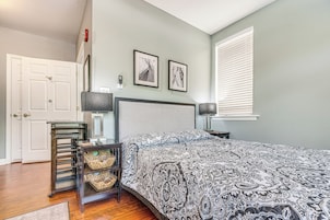 Un dormitorio con cama, mesita de noche, lámpara, silla y puerta.