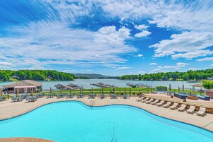 A swimming pool with lounge chairs and a view of a lake and mountains.