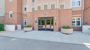 A brick building with a central entrance, large planters, and a parking lot in the foreground. - Steps to Smith Mountain Lake: Unit w/ Pool Access! (Huddleston)