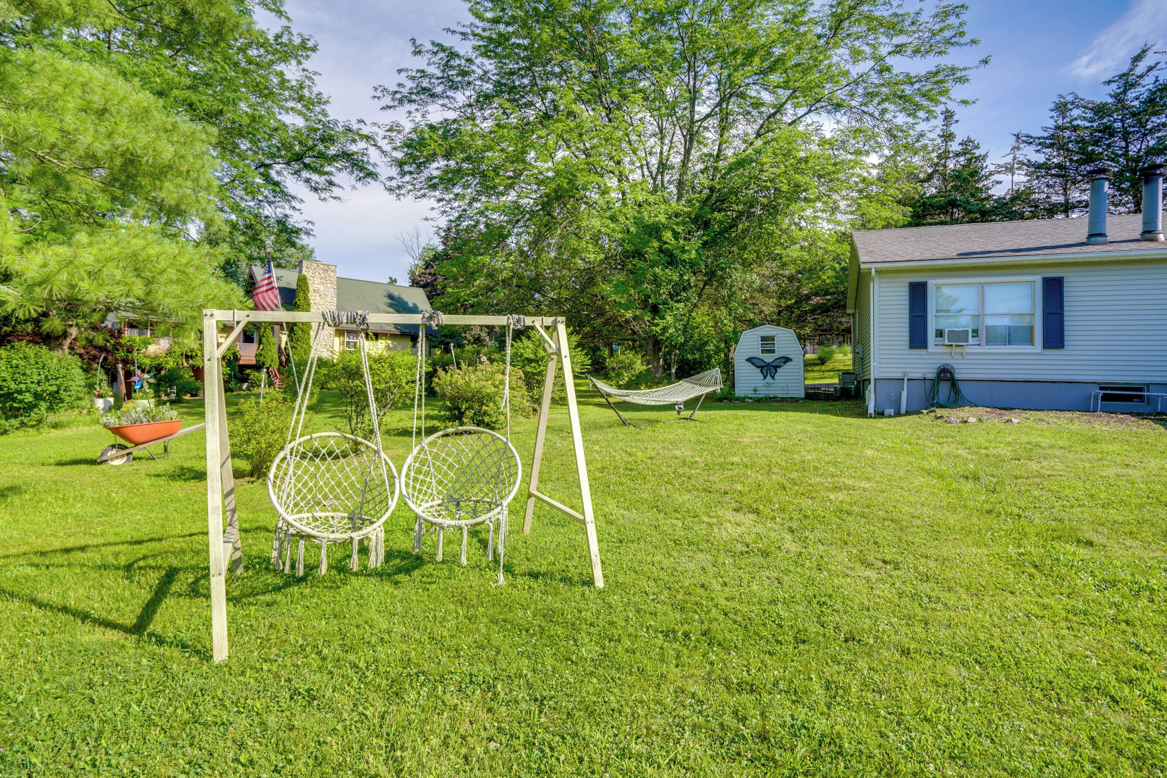 A backyard with a swing set, a hammock, and a small shed.