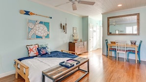 A bedroom with a bed, a wooden nightstand, a desk with chairs, a ceiling fan, and a large mirror. - Walk to Indian Shores Beach + Pool: Sunny Condo (Indian Shores)