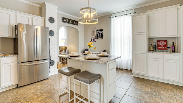 A modern kitchen with white cabinetry, a stainless steel refrigerator, and a central island with stools. - Dog-friendly Home w/ Yard, 6 Mi to Louisville! (New Albany)