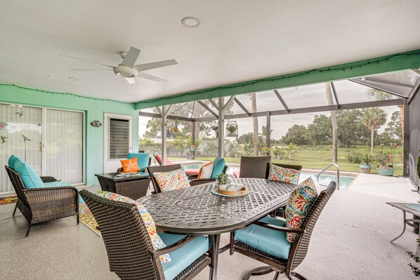 A covered patio with wicker furniture, a ceiling fan, and a view of the outdoors. - Saltwater Pool Coastal Family Retreat (Port Charlotte)