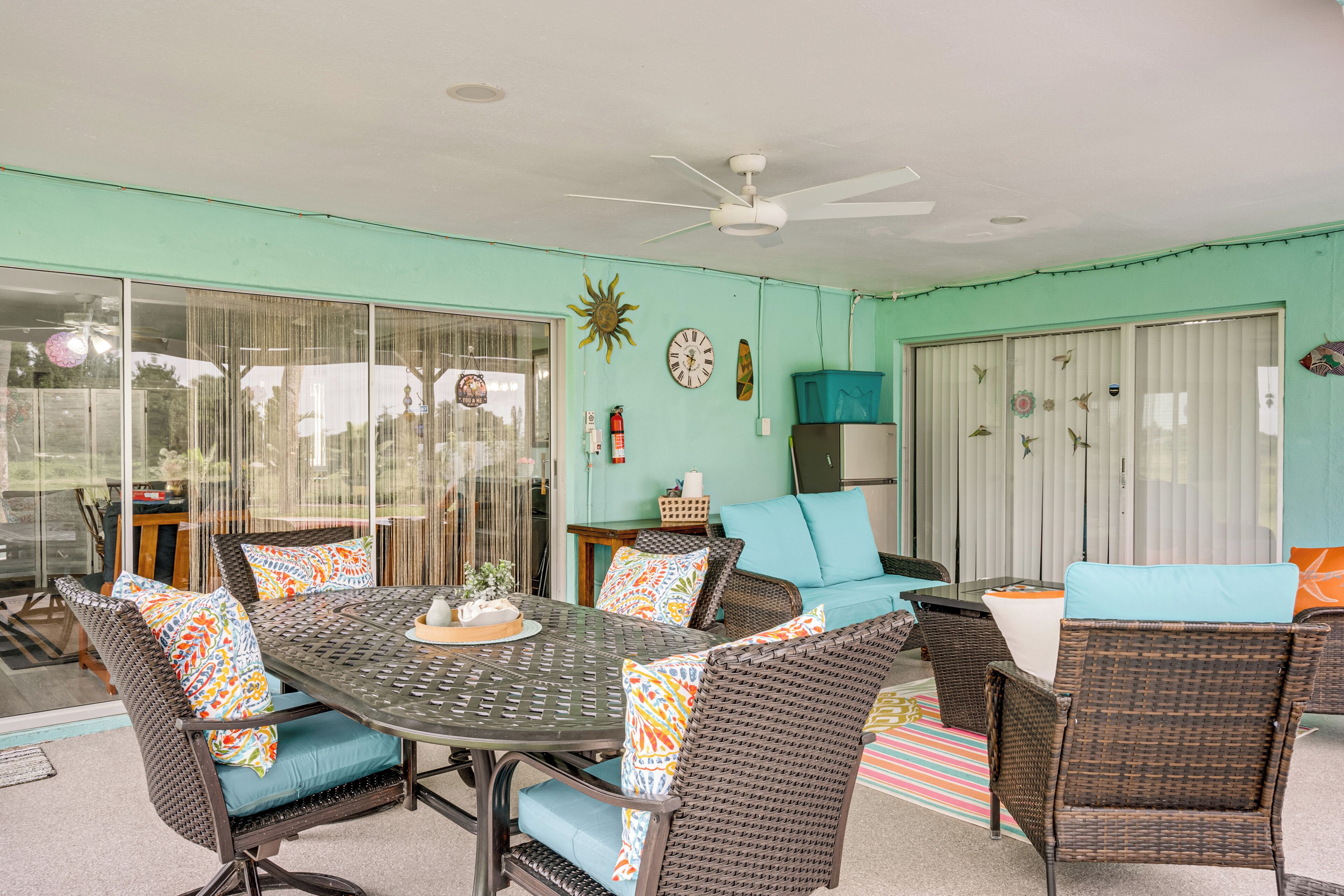 A dining area with wicker furniture, a ceiling fan, and a large window.