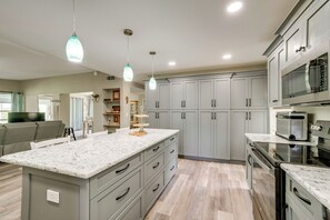A modern kitchen with grey cabinets, a marble countertop, and stainless steel appliances. - Saltwater Pool Coastal Family Retreat (Port Charlotte)
