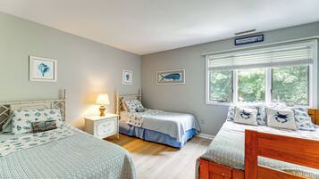 A bedroom with two beds, a nightstand, a lamp, and framed artwork on the walls.