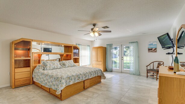 A bedroom with a bed, wooden wardrobe, desk, and a ceiling fan. - Sunny Sarasota Stay: Screened Pool + Pet Friendly (Sarasota)