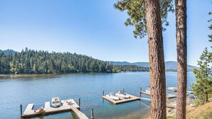 A lake with clear water, surrounded by a forest and mountains. There are docks with boats and a small dock with a boat. - Lake Lover's Paradise: Waterfront Home in Hayden! (Hayden)