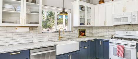 A modern kitchen with white cabinets, a stainless steel dishwasher, a white stove, and a red and white checkered towel hanging on the oven.