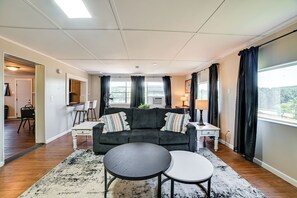 Ein Wohnzimmer mit einem dunkelgrauen Sofa, zwei weißen Beistelltischen, einem runden Couchtisch und einem schwarz-weißen Teppich.