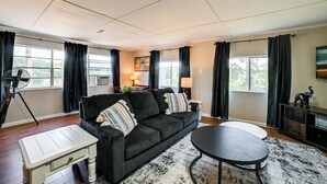 A living room with a black sofa, a small white table, a round black table, and a black and white rug. - Private Dock & Slip: Kentucky Lake Cottage! (Buchanan)