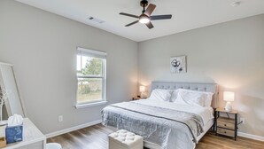 A bedroom with a bed, bedside tables, a ceiling fan, a window, and a small desk with a chair. - Family Getaway Near Lake Hartwell + Tugaloo Trails (Lavonia)