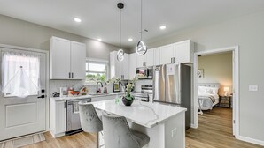 A modern kitchen with white cabinets, stainless steel appliances, and a central island with bar stools. - Family Getaway Near Lake Hartwell + Tugaloo Trails (Lavonia)