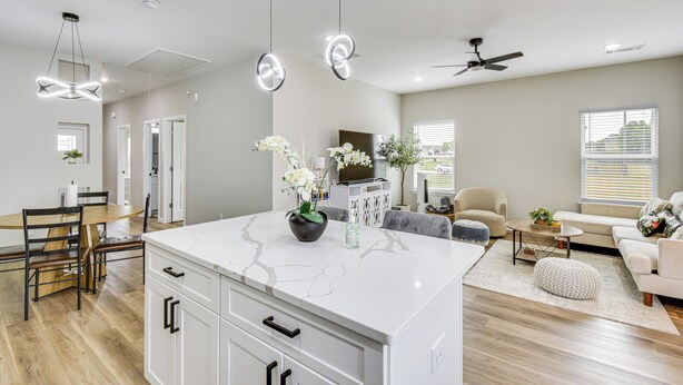 A modern kitchen with a marble countertop, a dining area with a wooden table and chairs, a living room with a sofa and a TV, and a ceiling fan. - Family Getaway Near Lake Hartwell + Tugaloo Trails (Lavonia)