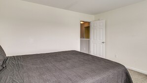 A bedroom with a bed, white walls, and a door leading to another room. - Spacious Home w/ Screened Patio in Pooler! (Pooler)
