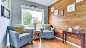 Una habitación con dos sillones azules, una mesita de madera y una pared de madera con cuadros.