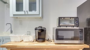 A kitchen with a microwave, toaster, coffee maker, and two baskets on a wooden countertop. - Easy Highway Access: Low-key Norcross Studio! (Norcross)