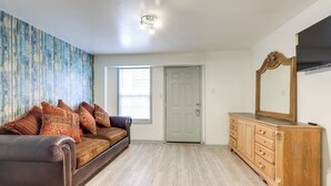 A room with a brown leather sofa, wooden dresser, and a large mirror. - Easy Highway Access: Low-key Norcross Studio! (Norcross)