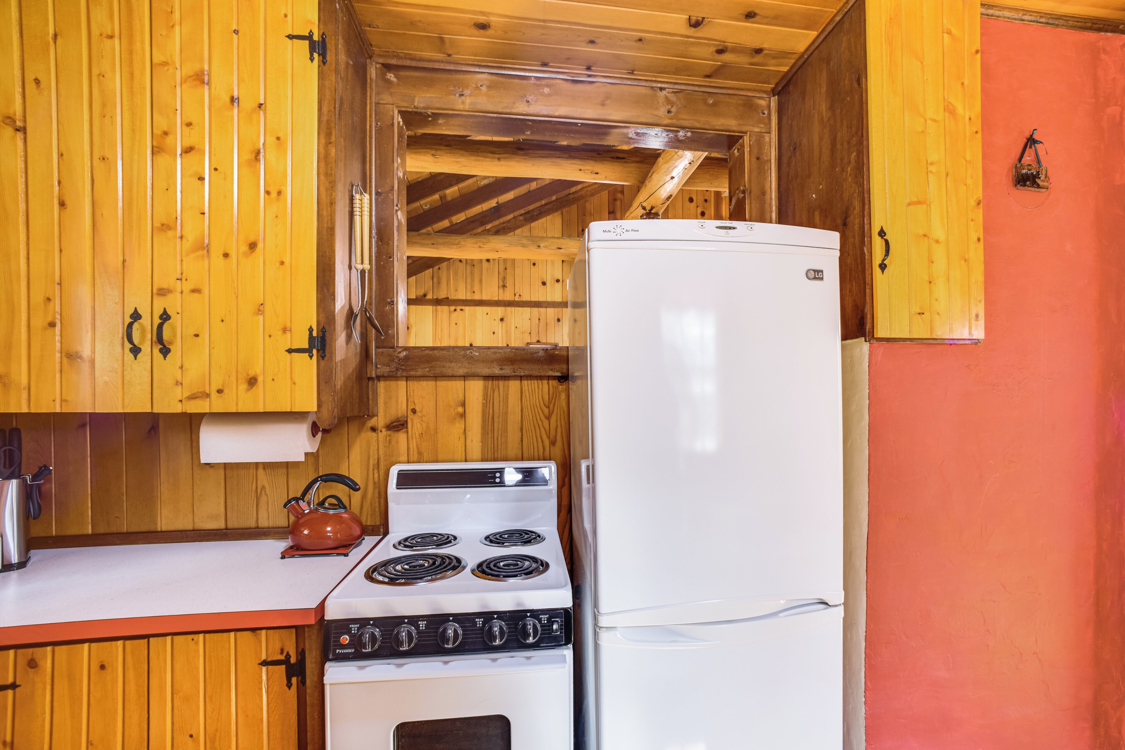 Eine kleine Küche mit Holzschränken, einem Herd und einem Kühlschrank.