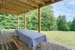 A covered picnic area with a checkered table and bench, surrounded by a natural landscape.