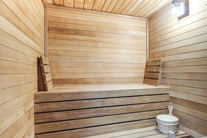 A sauna with wooden walls and benches, a small window, and a wooden bench with a handle.