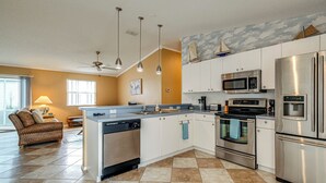 A modern kitchen with white cabinets, stainless steel appliances, and a checkered tile floor. - 2BR Pet-friendly Vacation Rental The Villages! (Lady Lake)