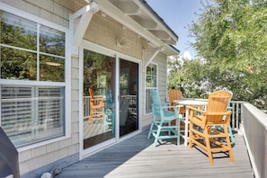 A covered deck with outdoor furniture and a sliding glass door. - Steps to Ocean: Luxe Kure Beach Home w/ Game Room (Kure Beach)
